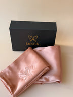Pink satin scarf with embroidered logo in front of a black box with 'LuxSilq' branding.
champagne rose
