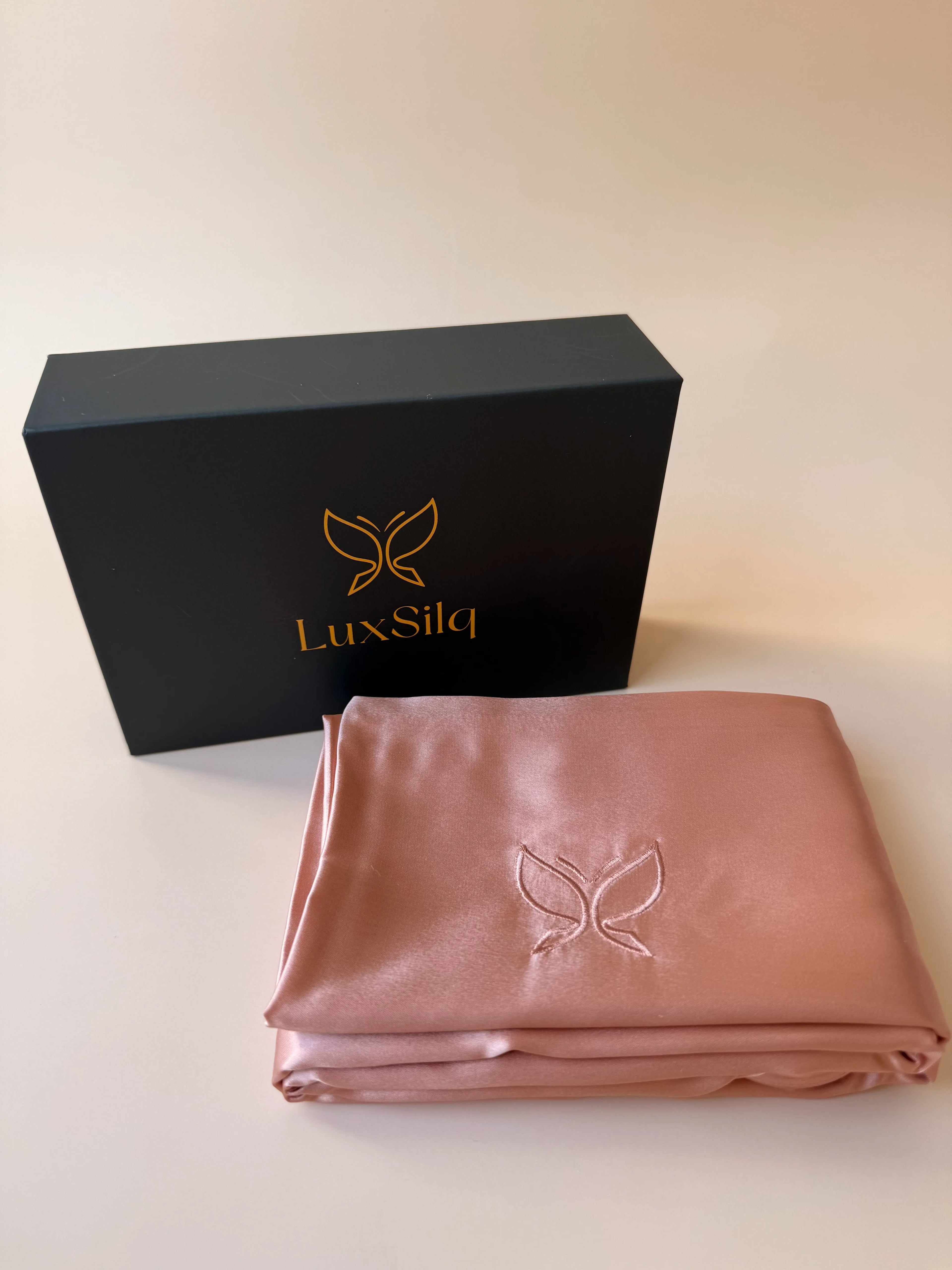 LuxSilq pink satin sheet with black box on a light beige background
champagne rose